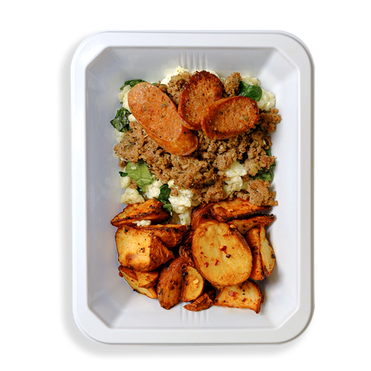 A vibrant and hearty meal arranged in a white takeout container, featuring seasoned ground turkey with a golden-brown sear layered over fluffy scrambled egg whites and tender, wilted spinach. On the side, crispy roasted red potatoes with caramelized edges bring a satisfying crunch. The dish is topped with slices of bison jalapeño cheddar sausage, dotted with melted cheese and green jalapeño pieces for a spicy, savory kick. Perfect for anyone short on time but craving a flavorful, wholesome meal.