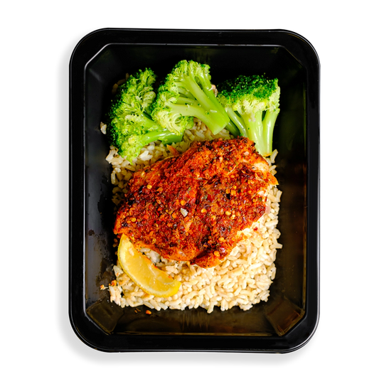 This salmon looks so tasty. It is heavily seasoned with a red seasoning and is served on top of brown rice accompanied by three pieces of broccoli and a lemon wedge. This meal is packaged in a to-go container which makes me think this is a healthy meal prepared and sold to people on to go or people who like to have healthy prepared meals delivered to their hous.
