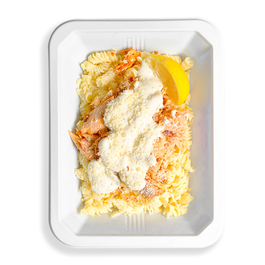 Light-colored dish of shredded roasted salmon on gluten-free pasta, coated in a house-made Alfredo and parmesan blend, softly filling the white to-go tray with creamy comfort. But comfort aside this looks like the perfect health meal that is prepared for people who love eating clean and are too busy to always be cooking.