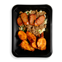 A colorful meal featuring seasoned ground turkey with a golden-brown sear, resting atop fluffy white scrambled egg whites mixed with wilted green spinach. On the side, crispy roasted red potatoes with a caramelized edge add texture, while slices of bison jalapeño cheddar sausage, speckled with melted cheese and bits of green jalapeño, crown the dish with a bold, savory finish.  All this fills a black takeout container and is for those who are sometimes too busy to cook but want to still eat delicious food.