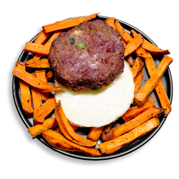 A hearty and colorful healthy prepared meal featuring a seared ground bison patty perched atop a perfectly round egg white medallion, surrounded by a generous serving of roasted sweet potato fries. Flecked with green onion and celery, and seasoned with a bold blend of roasted garlic, cumin, and Creole spices, this high-protein dish delivers balanced fuel for any time of day.
