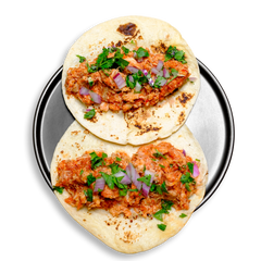 Top-down view of a plated health food dish featuring two lightly toasted flour tortillas stuffed with slow-cooked chicken thigh in a house-made spicy tomato-chipotle sauce. Garnished with diced red onions and fresh cilantro leaves, this protein-rich healthy meal prep option delivers bold flavor in every bite while keeping ingredients clean and satisfying.