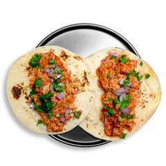 A duo of soft flour tortillas filled with juicy shredded chicken tinga, infused with roasted tomatoes, chipotle peppers, and garlic. Topped with a pop of red onion and leafy cilantro, these tacos are served on a sleek metal dish—perfect as a high-protein, flavor-packed healthy prepared meal for lunch, dinner, or meal prep rotation.