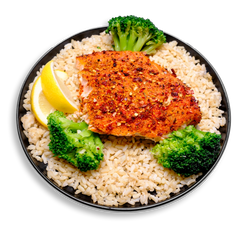 A golden, perfectly baked Atlantic salmon fillet sits atop a bed of fluffy parboiled brown rice, seasoned with a subtle blend of lemon pepper, garlic, and herbs. Bright green steamed broccoli florets surround the salmon, while two fresh lemon wedges rest on the side, adding a citrusy pop. A wholesome and delicious example of clean, healthy meal prep.