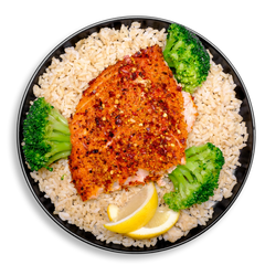 This nutrient-packed plate features a fillet of roasted salmon encrusted with crushed spices and garlic flakes, nestled on a generous serving of tender brown rice. The salmon is flanked by vibrant, lightly steamed broccoli and garnished with lemon wedges, creating a well-rounded, healthy prepared meal that’s rich in protein, fiber, and heart-healthy fats.
