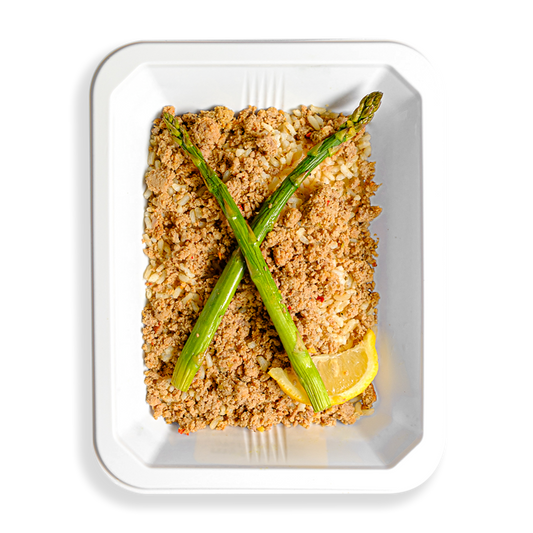 A takeout container holds a serving of ground turkey over a bed of rice, topped with two asparagus stalks and a fresh lemon wedge. The meal’s presentation suggests it is a nutritious, portion-controlled option, ideal for someone focused on weight loss or muscle gain.