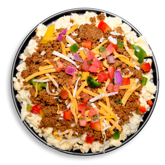 A black plate filled with a protein-rich egg scramble made from a 4:1 egg white to yolk blend, generously layered with savory ground turkey, roasted corn, and peppers. A medley of toppings—sharp cheddar cheese, juicy diced roma tomatoes, red onion, jalapeños, and fresh cilantro—brings a Tex-Mex flair to this balanced and healthy prepared meal perfect for breakfast, lunch, or dinner.