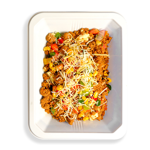 Hearty and vibrant scramble with ground turkey, egg whites, roasted veggies, and cheese—fuel for active, health-conscious lifestyles. This food fills a white togo container and appears to be for people who want to eat well while still eating clean healthy prepared foods.