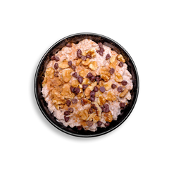 Top view of a wholesome health food breakfast in a black bowl showcasing gluten-free rolled oats infused with vanilla protein and cinnamon. This creamy oatmeal is topped with toasted walnuts and semi-sweet chocolate chips, delivering a comforting, high-protein, plant-based option ideal for healthy meal prep enthusiasts seeking a naturally sweet, filling start to the day.
