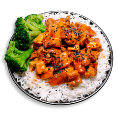 A vibrant healthy prepared meal of tender chicken thigh chunks coated in a bright, tangy orange-ginger glaze and garnished with black sesame seeds. Served over a fluffy bed of white basmati rice with a generous side of steamed broccoli, this high-protein, low-carb health food plate brings balance, color, and bold flavor to your healthy meal prep.