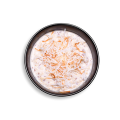 A black bowl filled with creamy overnight oats made from Greek yogurt, rolled oats, chia seeds, and honey, topped with a generous handful of golden toasted coconut flakes. The smooth, thick texture of this healthy prepared meal contrasts with the crisp topping, offering a protein-rich and fiber-packed health food option ideal for healthy meal prep and busy mornings.