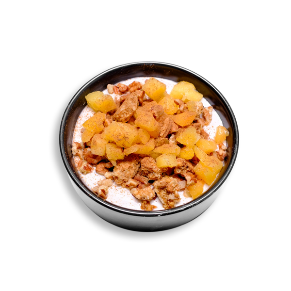 A three quarter view of a nutrient-dense yogurt parfait served in a sleek black bowl, brimming with health-conscious ingredients. The smooth Greek yogurt base is swirled with cinnamon and agave, then topped with juicy peach chunks, crisp granola, and rich pecan pieces. The contrast of textures and warm spice notes makes this a visually appetizing and wholesome option for those seeking a high-protein, low-fat healthy prepared meal.