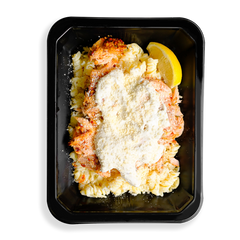 A pale, creamy salmon pasta with flakes of spice-rubbed Atlantic salmon over brown rice noodles, topped with parmesan and a light Alfredo sauce filling the black togo container.  This looks to be a hearty prepared meal designed for health conscious people who love eating.