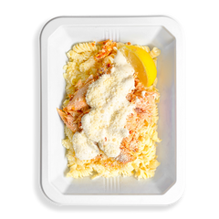 Light-colored dish of shredded roasted salmon on gluten-free pasta, coated in a house-made Alfredo and parmesan blend, softly filling the white to-go tray with creamy comfort.  But comfort aside this looks like the perfect health meal that is prepared for people who love eating clean and are too busy to always be cooking.