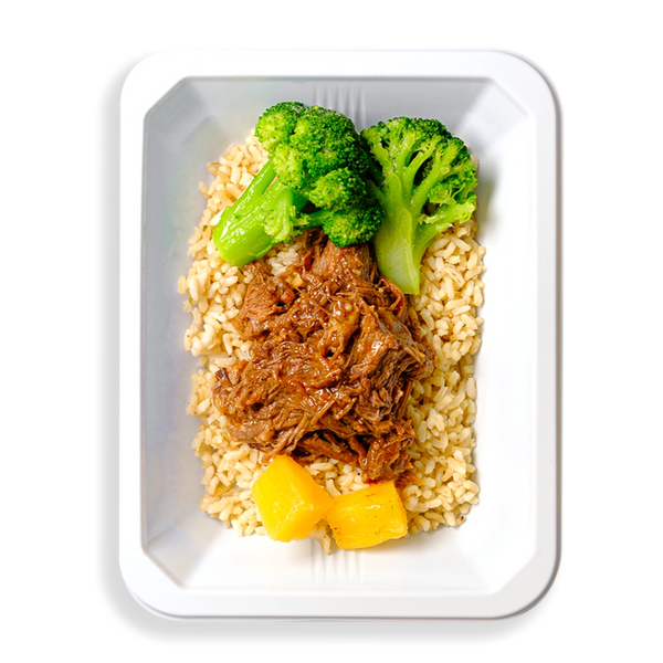 Two extremely green broccoli stalks alongside pulled beef with pineapple pieces are on a bed of brown rice in a white to-go container.  This food looks both very healthy and very flavorful all at ones.  The container the food is in makes me think this healthy meal is prepared for delivery or for instore pickup.